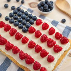 July 4 cake decorated to look like the USA flag with red raspberries and blueberries on white icing