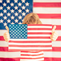 Child holding a painted flag as a 4th of July activity