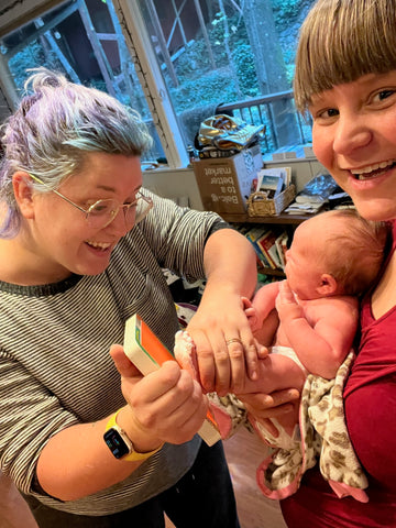 Caregivers push a baby's foot in paint to make Valentine's Day cards.