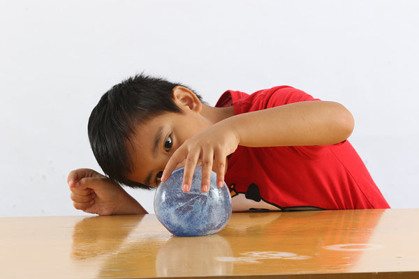 child looking at a blue colored ice sphere