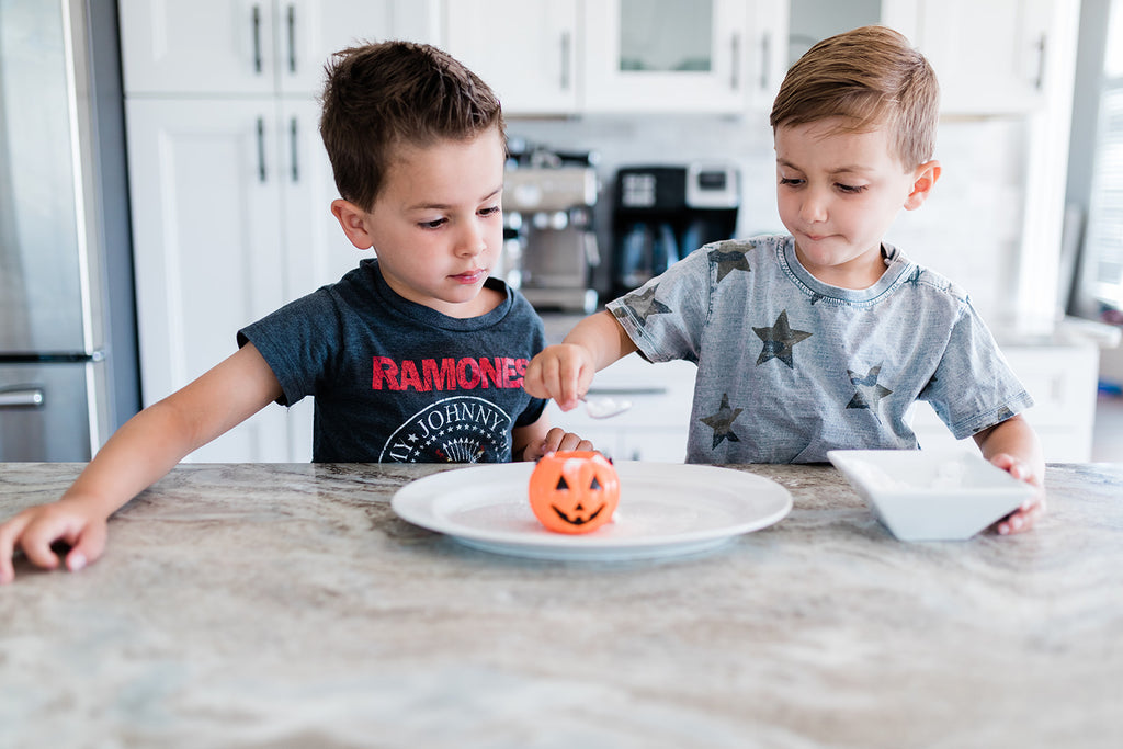 Two toddlers play with a pumpkin Halloween activity.