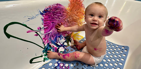 Baby playing with paint in the bathtub.