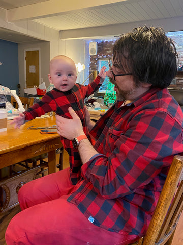 Father and baby wear the same plaid red shirt on Valentine's Day.