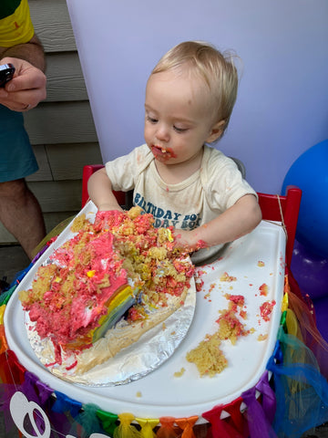 Baby plays with cake with red frosting for Valentine's Day.