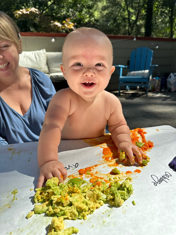 Baby plays with Christmas colored food like avocado.