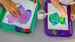 Hands rubbing paint ice cubes on paper