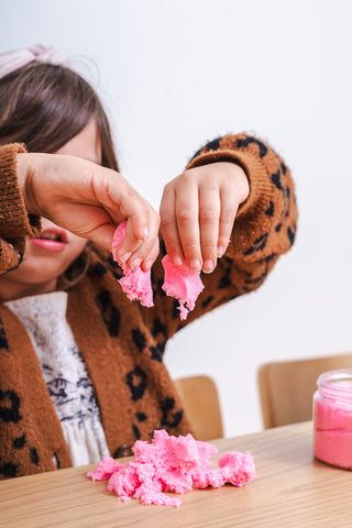 Child plays with pink magic sand for Valentine's Day.