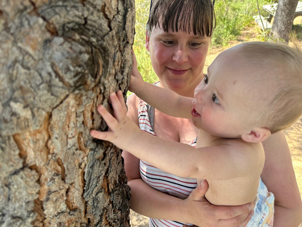 The Messy Play Baby touching a tree on a road trip.