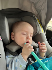 Messy Play Baby sleeps in car seat on road trip.