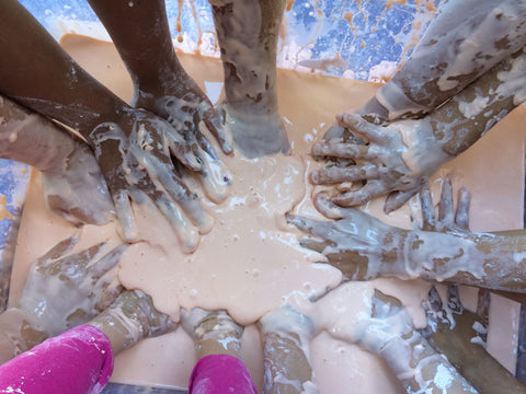 Lots of kid's hands in oobleck sensory play bin.