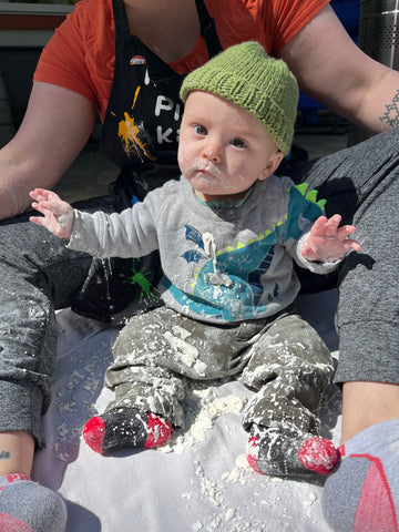 Baby sits in oobleck sensory play bin.