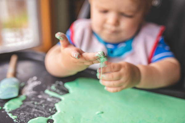 toddler playing with green sensory activity - oobleck