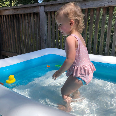 Child plays in outdoor blow up pool.