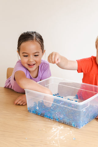 Children play with a winter sensory bin with water beads.