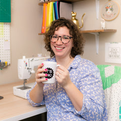 leah at her desk holding a coffee mug