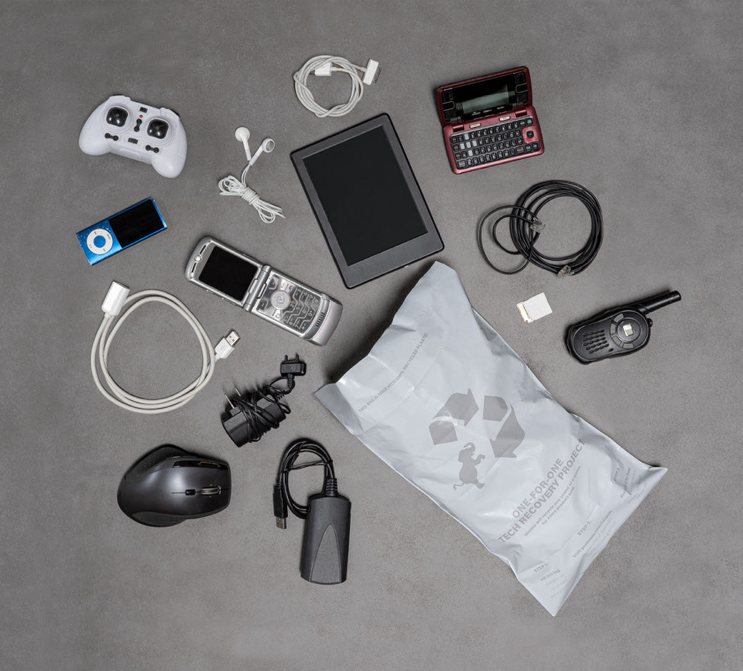 Various old electronics and accessories next to a recyclable tech recovery bag.