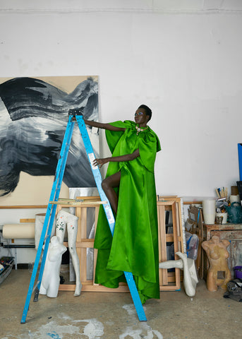 Image of model on ladder with green gown and necklace