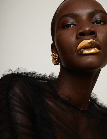 Black model in black feather top with gold knot earrings