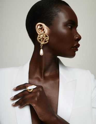 Black model in white top wearing gold jewelry