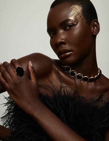 Black model in black feather top with cold and black enamel jewelry