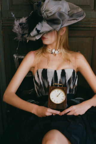 Image of model in fancy hat, strapless dress, and Schiaparelli necklace.