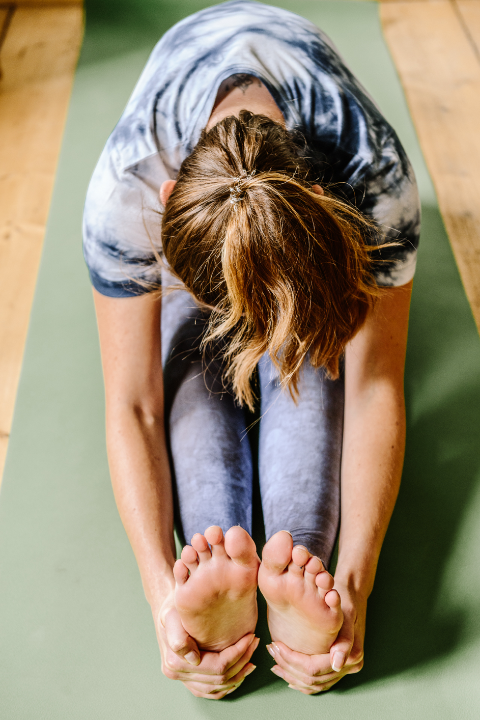 Woman bends forward on yoga mat