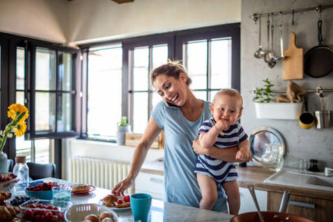 image of mom holding baby ad talking on phone in kitchen