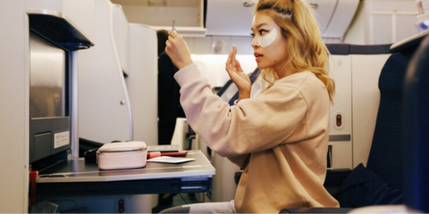 Girl wearing eyemask skincare inside airplane