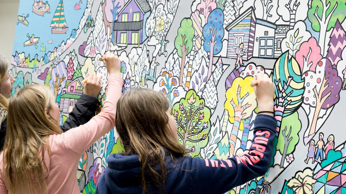family colouring a canvas mural together