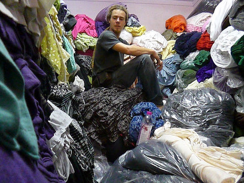 Richard sitting on top of a pile of deadstock fabric | fast fashion pollution | garment Industry Waste | sustainable fashion