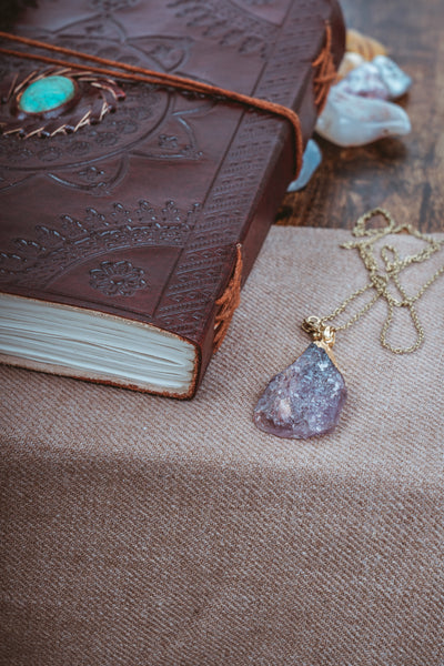 Leather journal on a table next to raw crystal boho necklace 