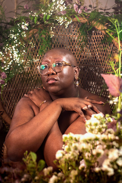 Margie, plus size and mental health advocate, surrounded by flowers wearing sustainable jewellery from ethical brand forage design