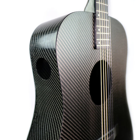 This picture shows a black carbon fiber guitar body with a traditional soundhole as well as a second 1 3/4 inch soundhole in the side of the upper lobe of the guitar's body.