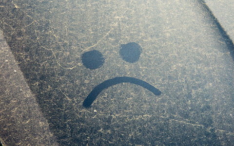 Car windscreen covered with pollen. Someone has drawn an unsmiley face in the dust because it can give you hay fever