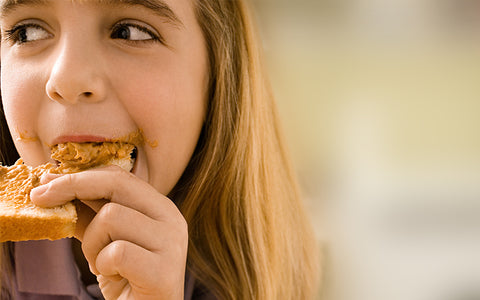 Girl eating a peanut butter sandwich – she didn’t react during her oral food challenge so isn’t allergic to peanuts