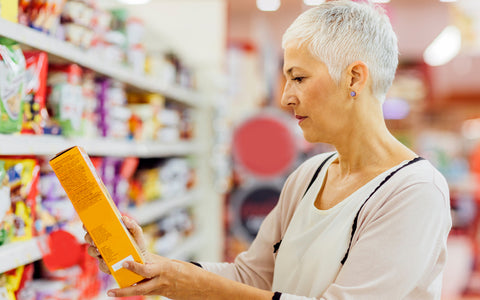 Woman reading the ingredients on food packaging at the supermarket – part of everyday life for someone with food allergies.