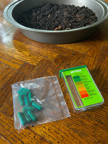 The pH testing container, color chart, capsules, and garden soil