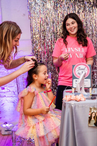 A kid receiving hair treatment at People partying during Boujie Mama Relaunch Party