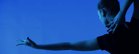 Dancer reaching out with her left hand on a blue background