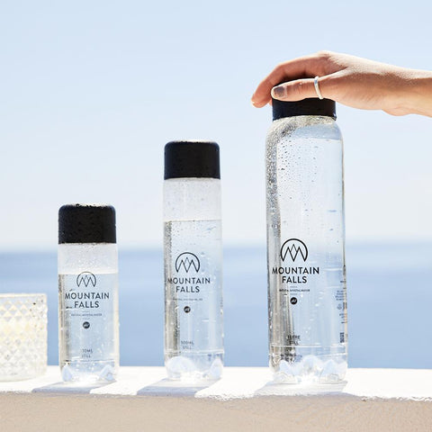 3 bottles of mineral water sitting alongside each other and beach in the background