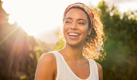Lady smiling with sun shining behind in background on her