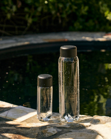 Sparkling Water and Mineral Water bottles sitting alongside each other with water in background