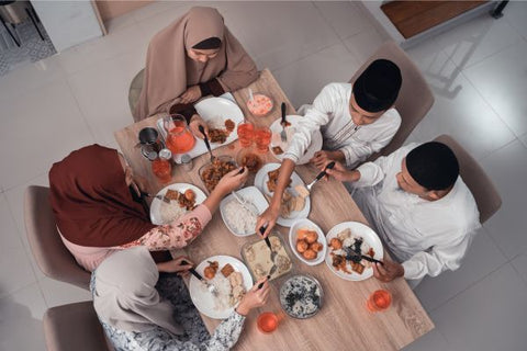 Muslim family, seated at a table, breaking their fast and enjoying iftar together.