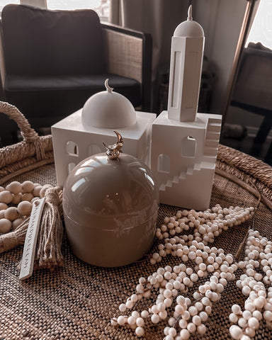 Moon Dome Jar, Pearls of North Africa Mosque & Minaret, and some large, wooden tasbih beads, inside a shallow, round, woven basket atop a coffee table.