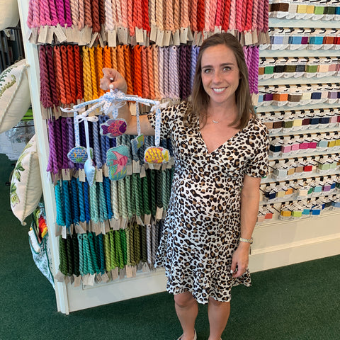 Customer holding finished needlepoint baby mobile