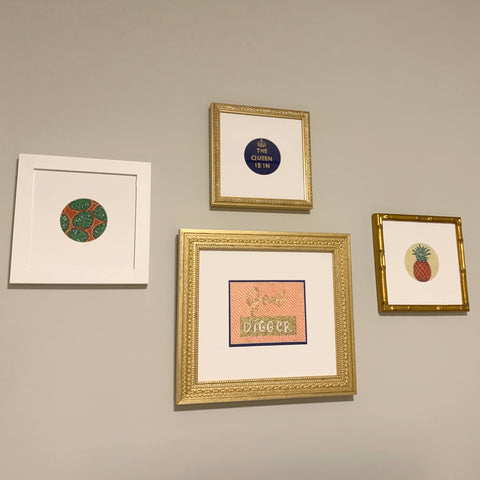 Various framed needlepoint pieces hanging on wall