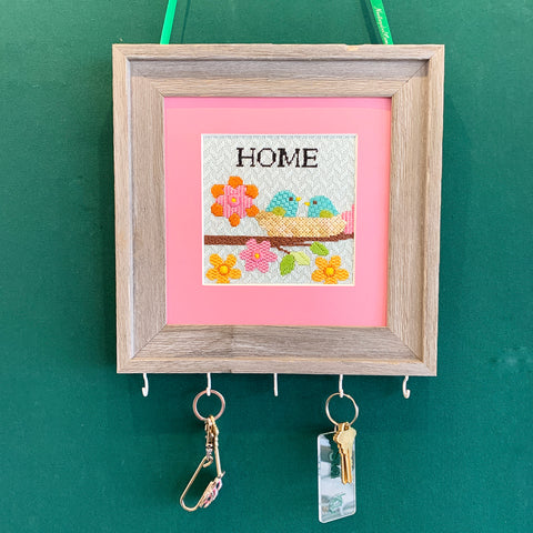 Finished Home needlepoint framed with hooks and ribbon