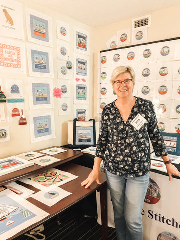 Elizabeth in her booth at a needlepoint trade show