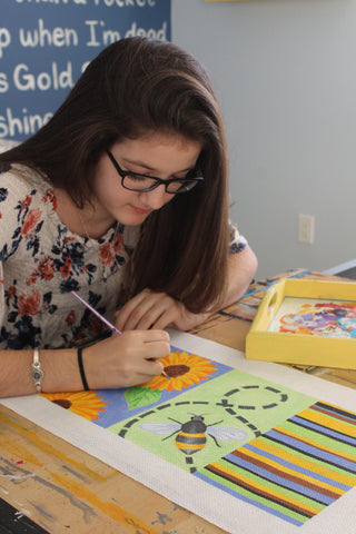 Madeleine Elizabeth painting a needlepoint canvas