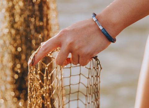 Hand with legend bracelet holding fishing net